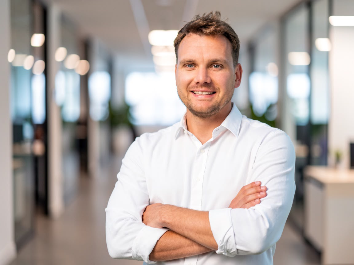 Kevin Simon mit verschränkten Armen in einem modernen Bürogebäude